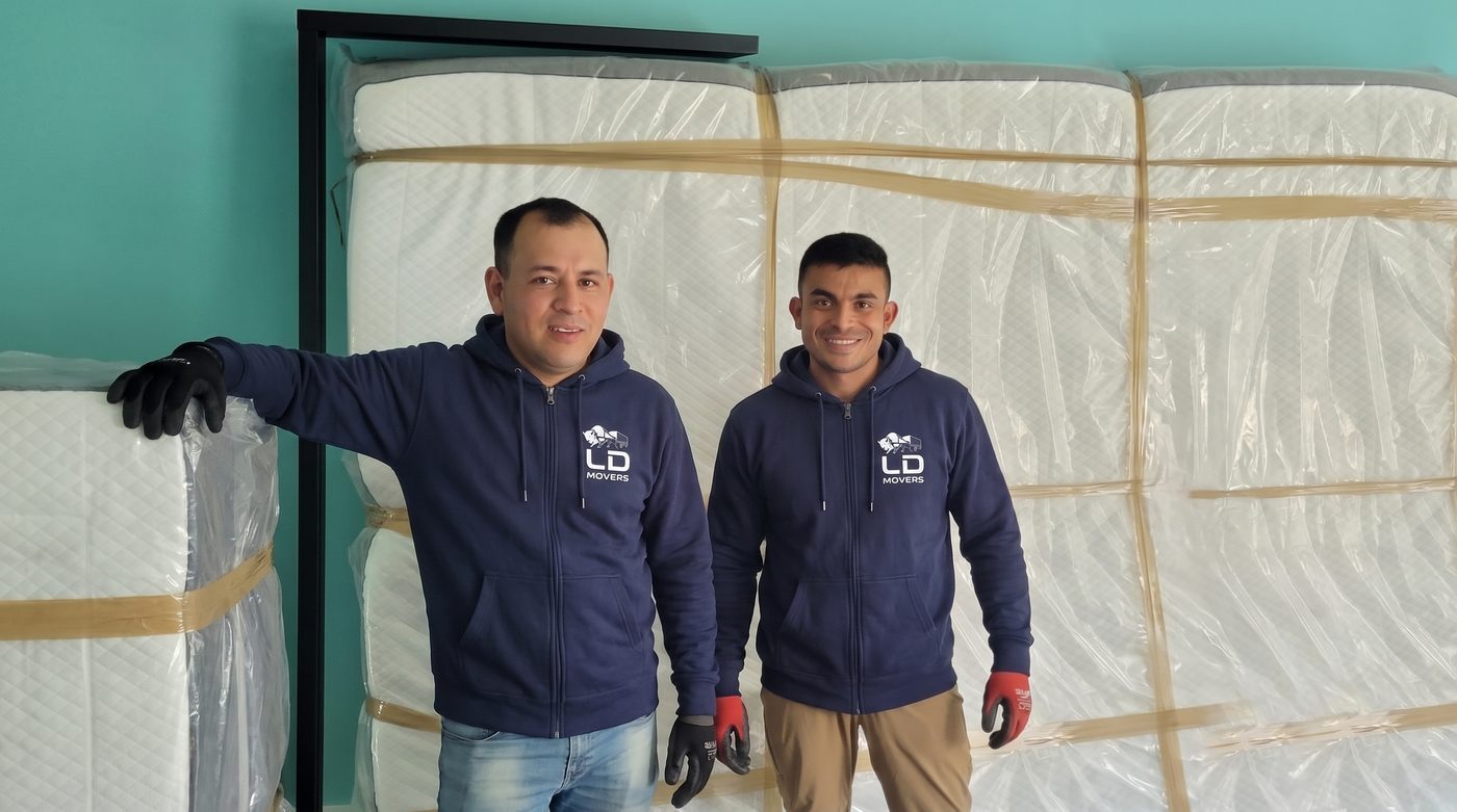 LD Movers apartment movers carrying a wrapped sofa through a building stairwell with floor protection in place