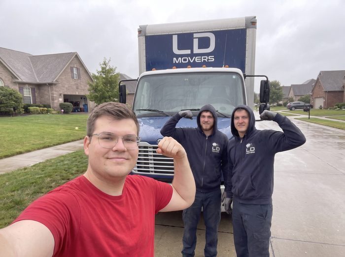 LD Movers customers and crew flexing beside the branded truck